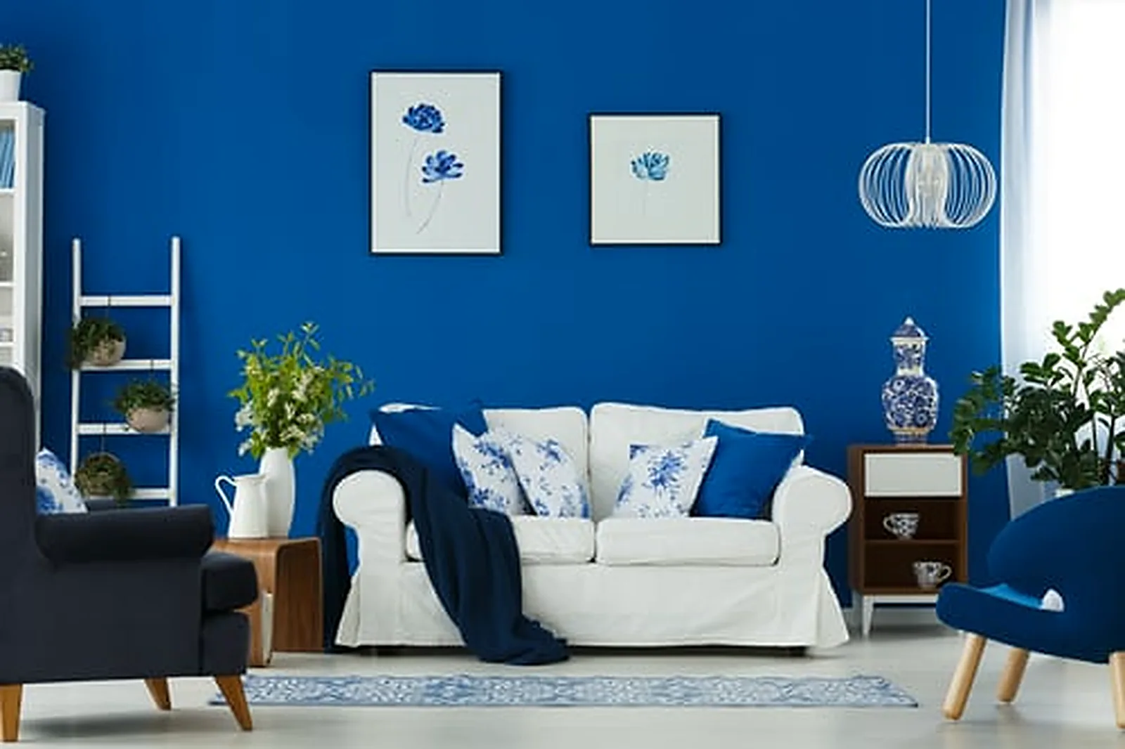 Bold blue accent wall paint color in a bright Bay Area living room with white sofa and fresh white trim