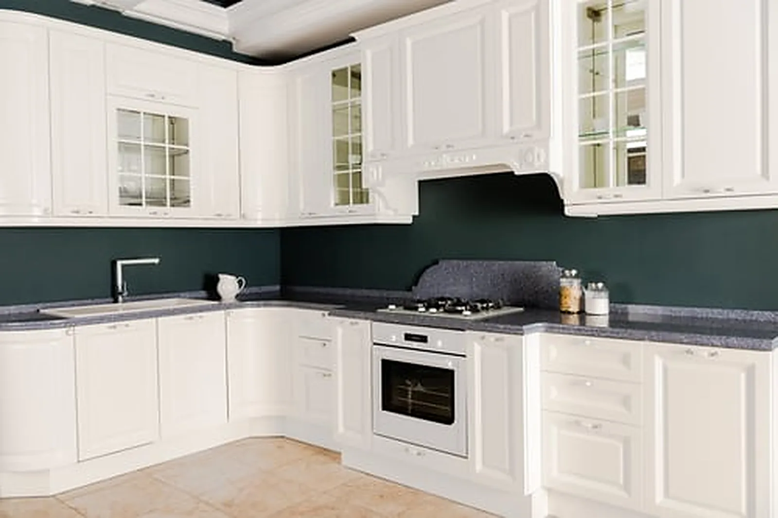 Freshly painted white kitchen cabinets against a deep green wall after professional cabinet refinishing