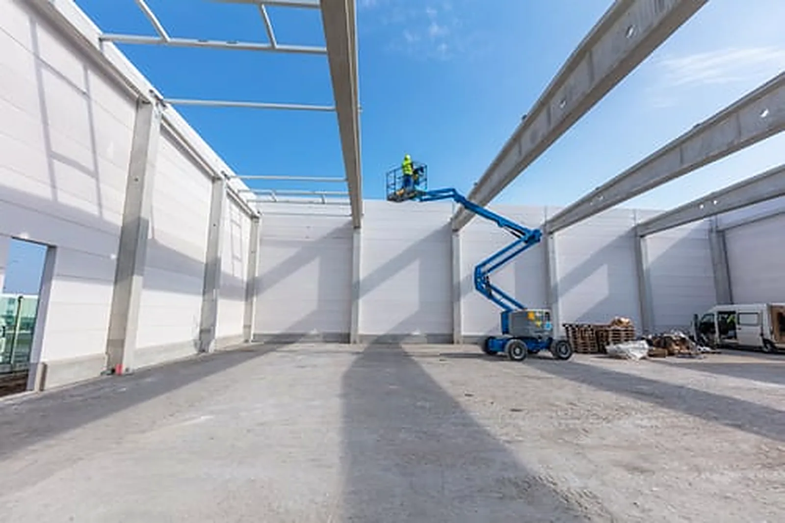 Commercial painter on a boom lift coating the exterior wall panels of a large commercial building