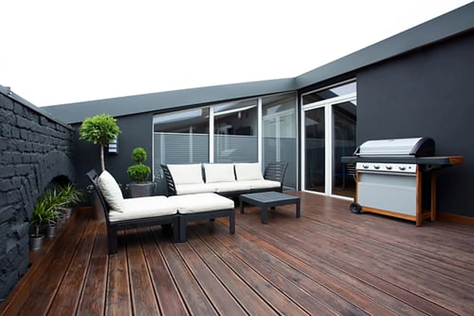 Freshly stained dark wood deck with modern patio furniture, showing professional deck staining and sealing results